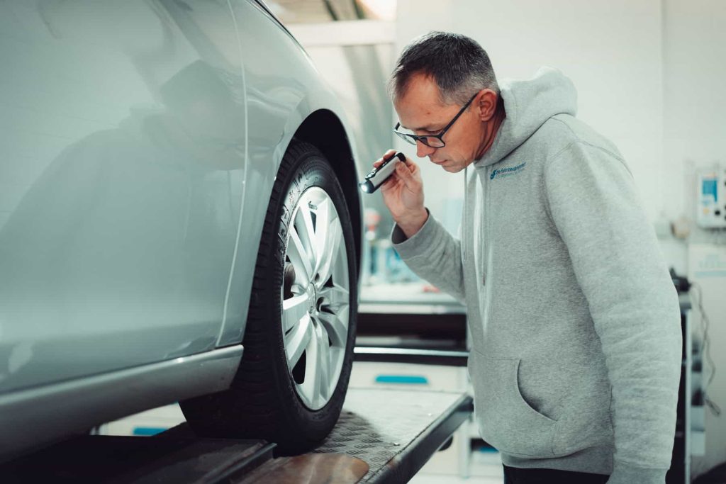 Mathias Warsinksi führt eine Inspektion mit einer Taschenlampe an der Bremsanlage durch