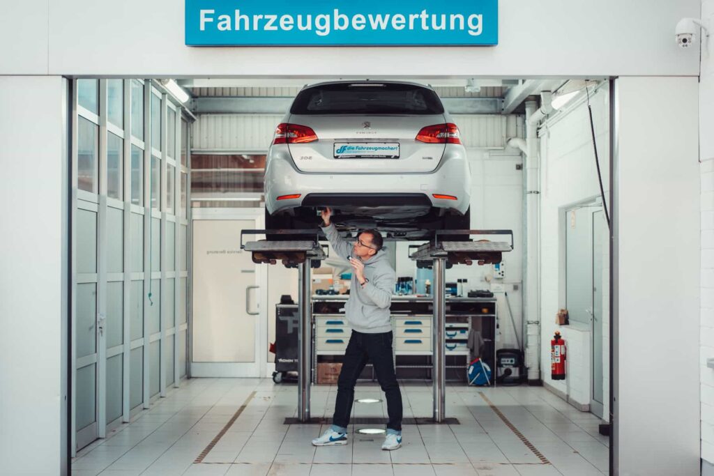Mathias Warsinki führt eine Inspektion an einem Auto auf der Hebebühne durch.